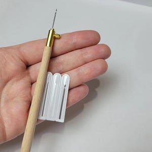 Peut inclure: Un outil de poinçon à manche en bois avec une pointe en métal doré et un ensemble d'aiguilles de remplacement dans un emballage en plastique transparent. L'outil de poinçon est conçu pour la broderie et le crochet de tapis.