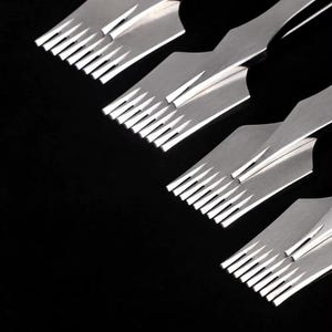 May include: Close-up of several silver leathercraft tools, each with a series of evenly spaced, sharp teeth. The tools are arranged diagonally against a black background, highlighting their metallic sheen and precision design. These tools are used for leather working.