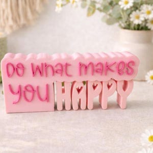 Könnte beinhalten: Eine weiße Keramik-Tasse mit schwarzem Henkel und dem Text "But First, Coffee" in schwarzer, handschriftlicher Schrift. Die Tasse steht auf einer weißen Oberfläche.