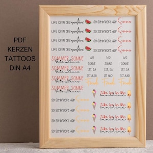 Puede incluir: Una impresión enmarcada con diseños de tatuajes temporales con temática de verano. Los diseños incluyen rodajas de sandía, conos de helado y frases como "Like ice in the sunshine" y "Summer Sonne Gute Laune". El marco es de madera clara.