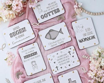 Puede incluir: Una colección de placas de madera blancas con temas religiosos, con texto grabado e ilustraciones. Las placas incluyen frases como "GOTTES" y "Konfirmation", con detalles decorativos dorados. El conjunto está sobre una tela rosa.