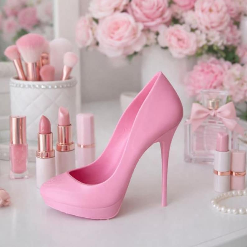May include: A pink high-heeled shoe is the focal point of this image, surrounded by beauty products. Makeup brushes, lipsticks, nail polish, and perfume are arranged on a white surface. A bouquet of pink roses is in the background, creating a feminine aesthetic.