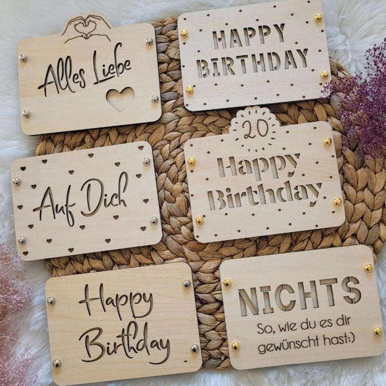 May include: Five wooden signs with different birthday greetings. The signs are decorated with hearts, dots, and gold accents. The greetings include "Alles Liebe", "Happy Birthday", "Auf Dich", "Happy Birthday 20", and "NICHTS So, wie du es dir gew&uuml;nscht hast."