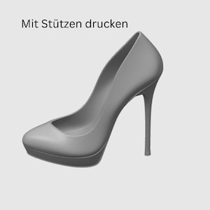 May include: A gray high-heeled pump with a platform sole. The shoe has a pointed toe and a slender stiletto heel. The text "Mit St&uuml;tzen drucken" is visible in the image.