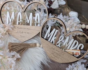 May include: Two wooden heart-shaped signs with the words "Mama" and "Mr. & Mrs."  The signs are decorated with dried flowers and have a rustic, farmhouse style.