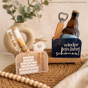 Könnte beinhalten: Ein hölzernes Geburtstagsgeschenk-Set mit einem kuchenförmigen Kartenhalter mit der Aufschrift Happy Birthday, einem kleinen Haus-Ornament, einem Flaschenöffner mit Holzgriff und einer braunen Bierflasche in einem dunkelblauen Halter mit dem Text wieder ein Jahr schöner.