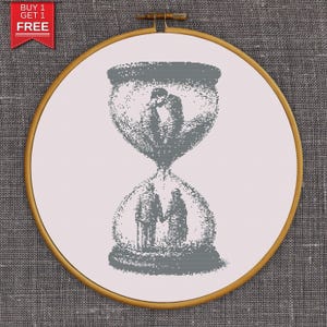 May include: A cross-stitch embroidery in a wooden hoop. The design features an hourglass shape with two couples, one embracing and the other holding hands. The text "BUY 1 GET 1 FREE" is in a red banner in the upper left corner.