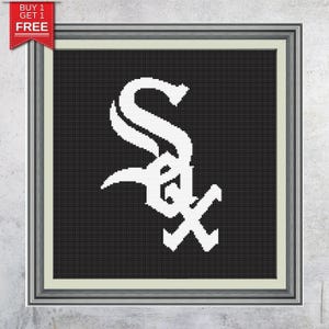 May include: Framed cross-stitch featuring the Chicago White Sox logo in white against a black background. The logo is the team's stylized "SOX" script. The frame is silver with a light green matting.