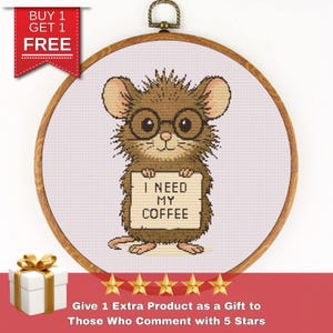 Puede incluir: Patrón de punto de cruz con un ratón de dibujos animados que lleva gafas y sostiene un cartel que dice "Necesito mi café".