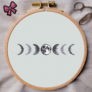 Puede incluir: Un aro de bordado de punto de cruz con fondo blanco y un diseño en blanco y negro de las fases de la luna. Las fases de la luna están en fila, comenzando con la luna nueva y terminando con la luna llena.