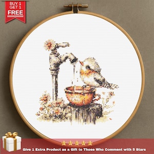 May include: Cross-stitch embroidery of a bird drinking from a teacup under a faucet. The artwork is framed in a wooden hoop. The image includes the text "BUY 1 GET 1 FREE" and "Give 1 Extra Product as a Gift to Those Who Comment with 5 Stars".