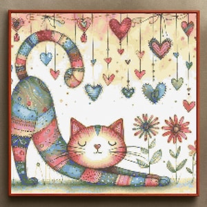 Puede incluir: Obra de arte de punto de cruz de un gato estirándose con un diseño de patchwork colorido. El gato está rodeado de corazones colgantes de varios colores y flores. La obra de arte está enmarcada en un marco de madera marrón.
