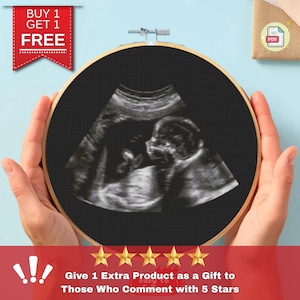 May include: A black and white ultrasound image of a baby in a round embroidery hoop. The image is held by a person's hands. The text "BUY 1 GET 1 FREE" is in the top left corner of the image. The text "Give 1 Extra Product as a Gift to Those Who Comment with 5 Stars" is at the bottom of the image.