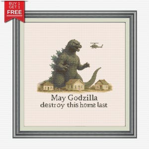 May include: Cross-stitch framed artwork featuring Godzilla, a helicopter, and houses. The text "May Godzilla destroy this home last" is below the image. The artwork is framed in a silver-colored frame with a "Buy 1 Get 1 Free" banner.