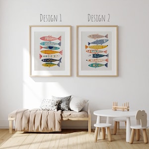 May include: Two framed art prints featuring colorful fish designs. The prints are labeled "Design 1" and "Design 2" at the top. The fish are in various colors, including red, blue, yellow, and orange, with decorative patterns. The artwork is displayed in a light-colored room.