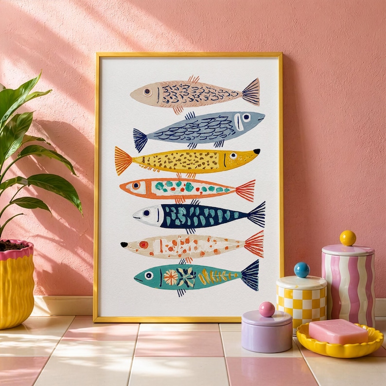 May include: A framed art print featuring seven stylized fish in various colors and patterns. The fish are arranged vertically against a white background, with a gold frame. The artwork is displayed on a pink and white tiled surface.