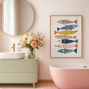 May include: A framed art print featuring seven colorful fish illustrations. The fish are in various colors, including pink, blue, yellow, and orange, with detailed patterns. The artwork is displayed in a bathroom setting with a pink bathtub and a light green vanity.