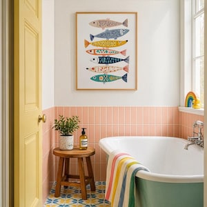 May include: A framed art print featuring seven colorful fish illustrations. The fish are in various colors and patterns, including blue, yellow, and orange. The artwork hangs above a bathtub with a colorful striped towel. A small wooden stool holds a plant and soap.