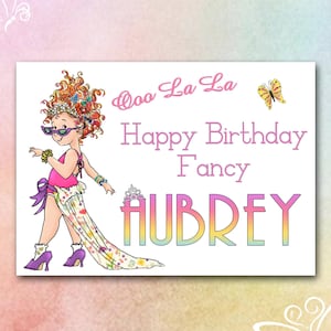 May include: A colorful birthday card featuring a cartoon girl with curly red hair wearing sunglasses and a pink dress. The card says "Ooo La La Happy Birthday Fancy Aubrey".