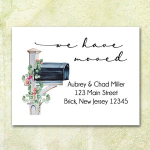 May include: A watercolor illustration of a mailbox with green leaves and pink flowers. The text "we have moved" is written above the mailbox. Below the mailbox is the text "Aubrey & Chad Miller, 123 Main Street, Brick, New Jersey 12345".