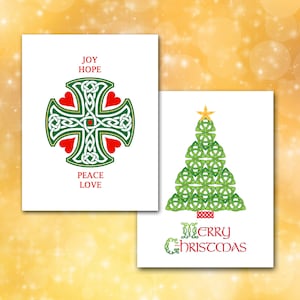 May include: Two white Christmas cards with Celtic knot designs. One card features a green cross with red hearts and the words "JOY HOPE PEACE LOVE." The other card shows a green Christmas tree with a gold star and the words "MERRY CHRISTMAS."