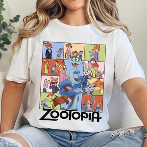 Peut inclure: T-shirt blanc avec un motif color&eacute; de personnages du film d'animation Zootopie. Le motif comprend une grille d'images avec le mot "Zootopia" en noir en bas. Le t-shirt est fait d'une mati&egrave;re douce.