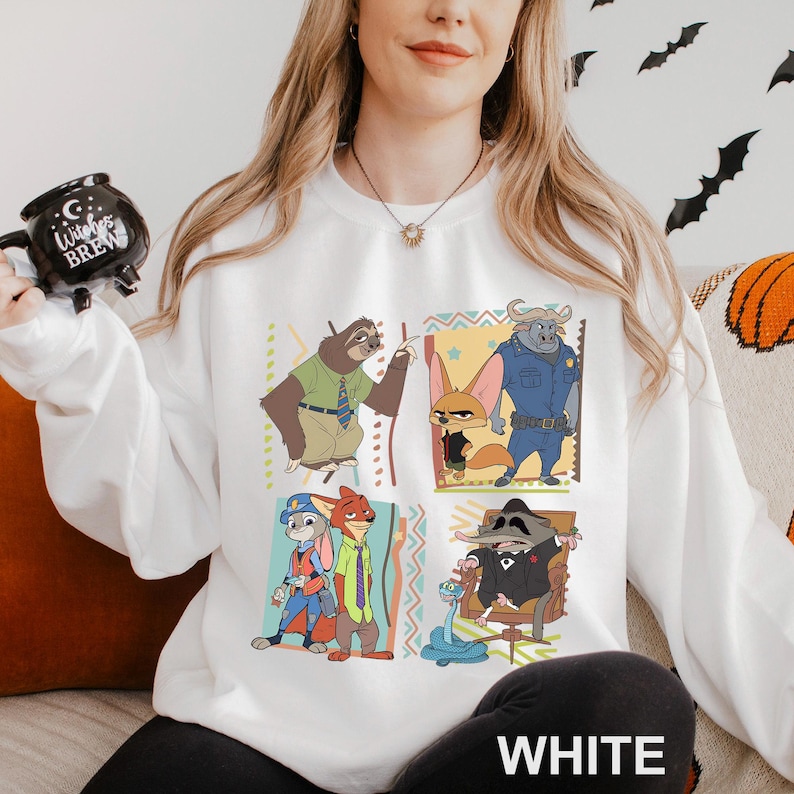 Puede incluir: Sudadera blanca con un colorido gr&aacute;fico de dibujos animados de personajes de una pel&iacute;cula de animaci&oacute;n. El gr&aacute;fico incluye un perezoso, un zorro, un b&uacute;falo y otros personajes. La palabra "WHITE" est&aacute; impresa en la parte inferior.