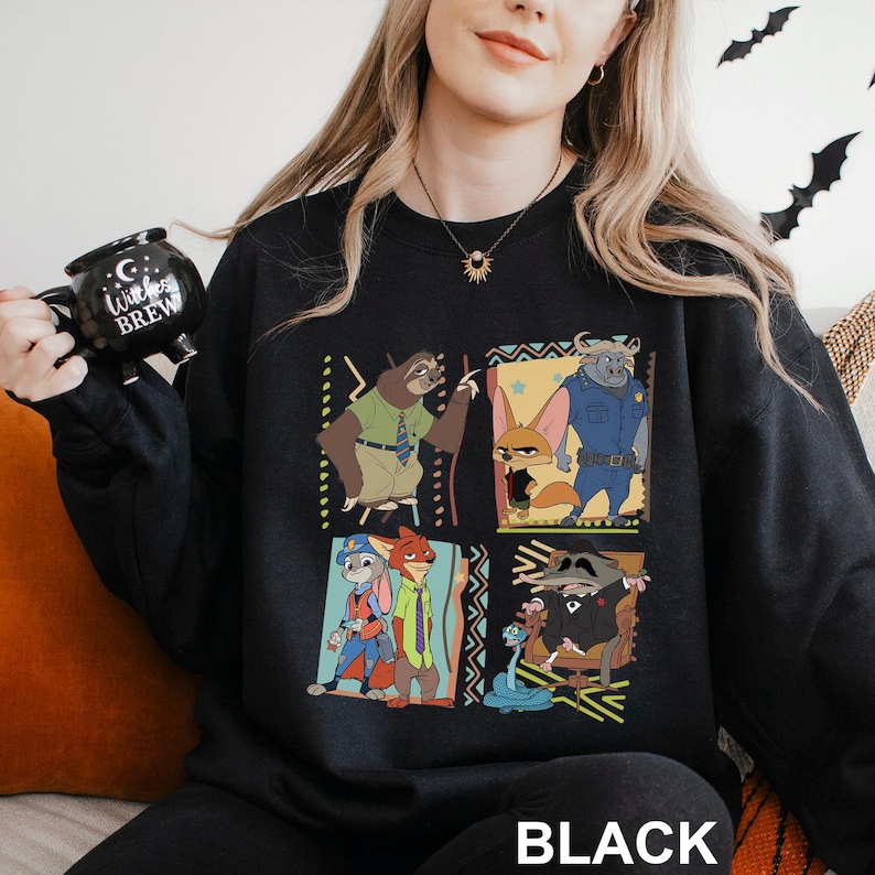 Puede incluir: Sudadera negra con un gr&aacute;fico colorido de personajes de la pel&iacute;cula animada Zootr&oacute;polis. El dise&ntilde;o incluye im&aacute;genes de un perezoso, un zorro y otros personajes en un patr&oacute;n de cuadr&iacute;cula. La palabra "BLACK" est&aacute; impresa en la parte inferior.