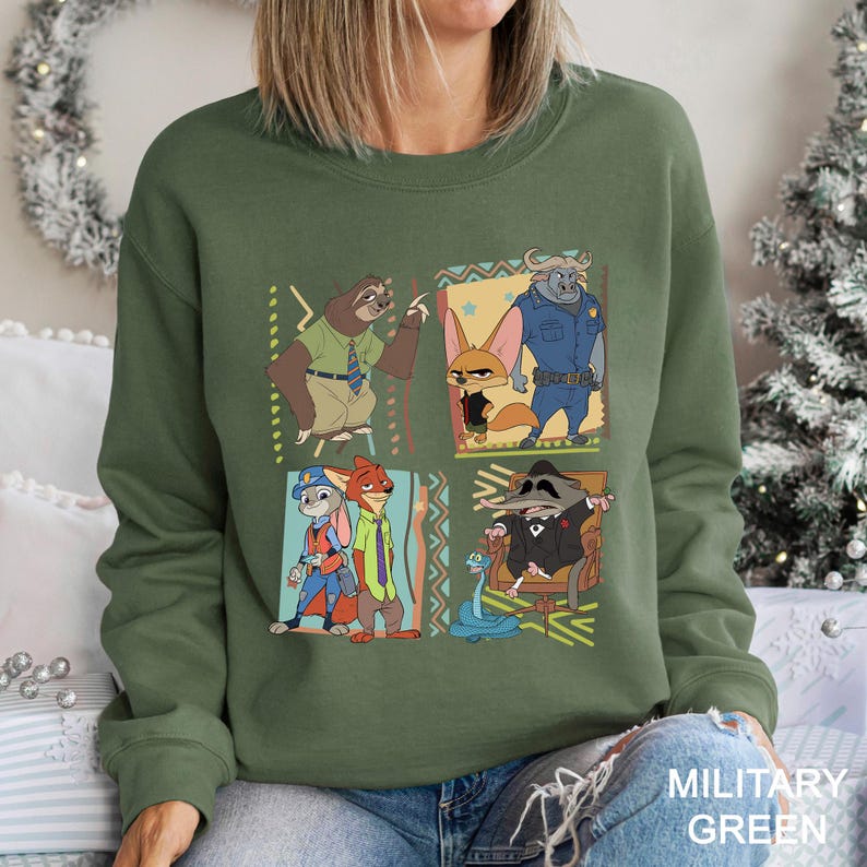 Puede incluir: Sudadera verde militar con un gr&aacute;fico colorido de personajes de Zootopia. El dise&ntilde;o incluye un perezoso, un zorro, un toro, un conejo y un mapache. La sudadera es de cuello redondo.