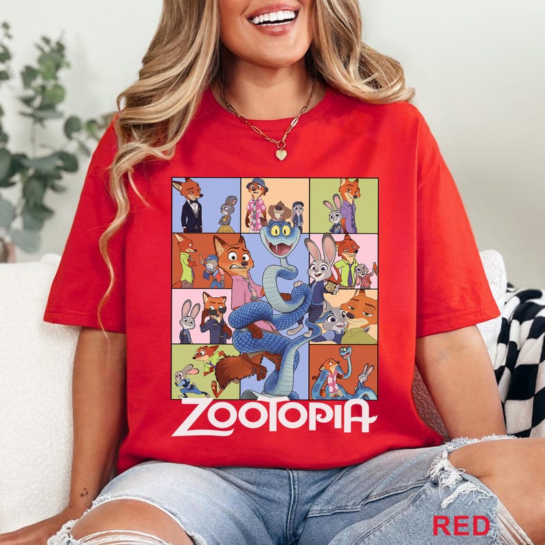 Peut inclure: T-shirt rouge avec un collage color&eacute; de personnages de Zootopia. Le design comprend Nick Wilde, Judy Hopps et d'autres personnages du film d'animation. Le mot "ZOOTOPIA" est imprim&eacute; en blanc en bas du motif.