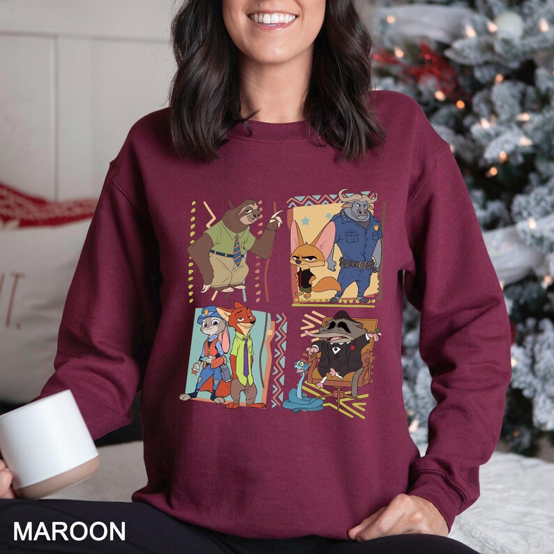 Puede incluir: Sudadera granate con un dise&ntilde;o de cuatro paneles con personajes de dibujos animados. Cada panel muestra un personaje diferente de una pel&iacute;cula, con detalles y patrones coloridos. La palabra "MAROON" est&aacute; impresa en la parte inferior.