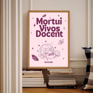 May include: Pink and purple framed print featuring a skull and flowers. The text on the print reads "Mortui Vivos Docent" and "Poeticadia".
