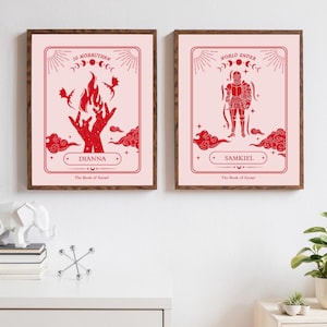 May include: Two framed prints with a pink background and red illustrations. The print on the left features a hand with flames and the text "Dianna, The Book of Angels, 16 Morruthen". The print on the right features a knight and the text "Samkiel, The Book of Angels, World Ender".