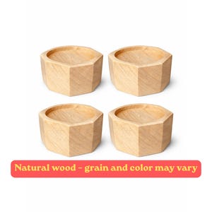 May include: Four light-coloured wooden hexagonal risers with visible grain patterns. Each piece features a flat top surface and angled sides. A red rectangular banner at the bottom contains the text: Natural wood - grain and colour may vary.