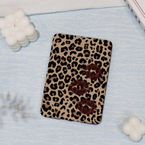 May include: A brown and tan leopard print phone case with a brown lip print design.