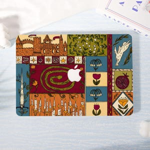May include: A colorful laptop skin featuring a patchwork design with a castle, snake, candles, flowers, and a rabbit. The skin has a white Apple logo in the center and is set against a light blue background. The design incorporates various colors.