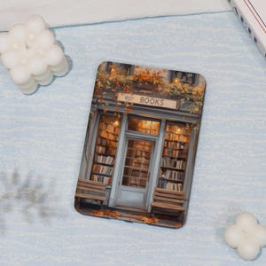 Könnte beinhalten: Ein Buchladen im Vintage-Stil mit einem Schild, auf dem "BÜCHER" über dem Eingang steht. Die Fassade ist mit Herbstlaub geschmückt und strahlt eine warme, einladende Atmosphäre aus.