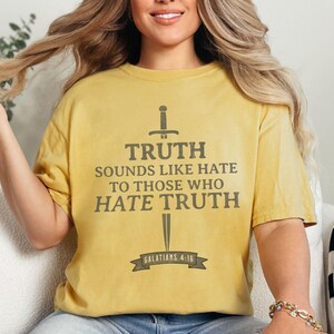 May include: Mustard yellow t-shirt with the text "TRUTH SOUNDS LIKE HATE TO THOSE WHO HATE TRUTH" in gray, with a sword graphic. The text includes the reference "GALATIANS 4:16".