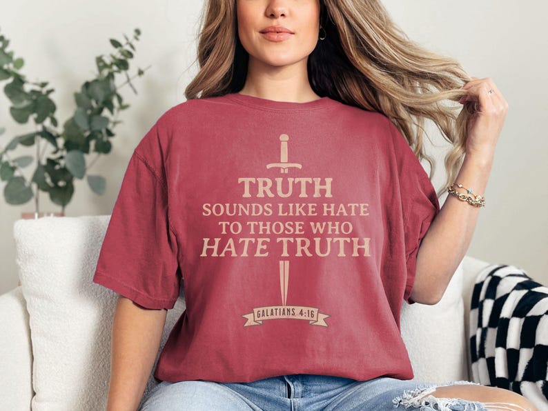 May include: A maroon t-shirt with the text "TRUTH sounds like hate to those who hate truth" in a light brown color. The shirt also features a sword and banner graphic. The text "Galatians 4:16" is printed on the banner.