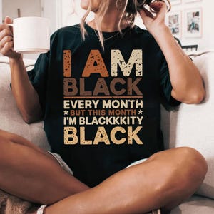 May include: Black t-shirt with the text "I am Black Every Month But This Month I'm Blackkkity Black" in a vintage style font.