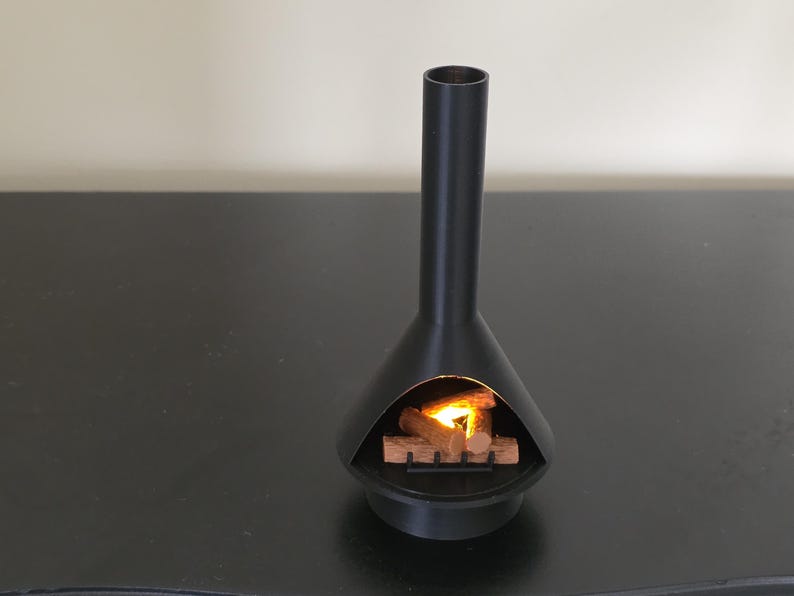 May include: A black, mid-century style fireplace with a tall chimney and a conical base. The fireplace has a glowing fire inside, with wooden logs and a warm, inviting light.