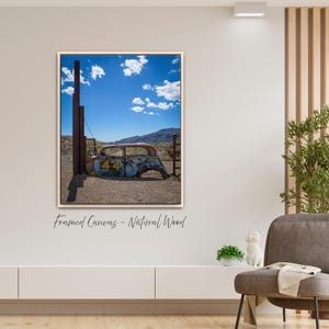 May include: Framed canvas print featuring a vintage car body with the number 44 on the side, set against a backdrop of a blue sky with clouds and a mountain range. The artwork is framed in natural wood.