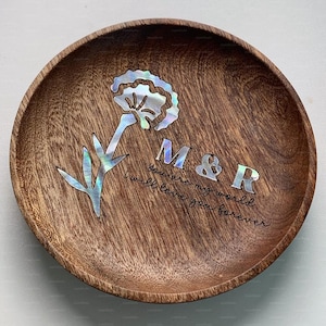 Könnte beinhalten: Runde dekorative Holzschale mit einem Blumen- und Blattdesign, eingelegt mit schillerndem Perlmutt. Die Schale hat die Initialen "M&R" und den Text "You are my world, I will love you forever."