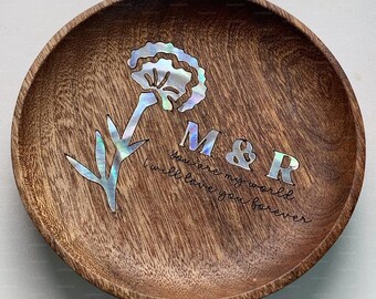 May include: Round wooden decorative bowl with a flower and leaf design inlaid with iridescent mother-of-pearl. The bowl has the initials "M&R" and the text "You are my world, I will love you forever."