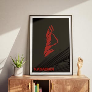 May include: Black and white framed poster with a red silhouette of a person with the word "KASABIAN" in red text at the bottom.