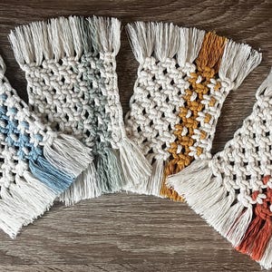 Può includere: Quattro sottobicchieri in macramè fatti a mano in una varietà di colori, tra cui blu, verde, giallo e arancione. Ogni sottobicchiere presenta un design intrecciato con un bordo a frange. Questi sottobicchieri decorativi sono perfetti.