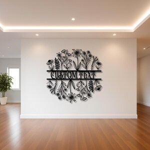 May include: Black metal floral wall art with the text "CUSTOM TEXT" in the center. The design features a circular arrangement of various flowers and foliage, suitable for home decor.