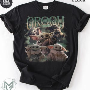 May include: A black short-sleeve t-shirt featuring a graphic print of multiple Grogu characters in various poses. The text GROGU is printed in a large, stylized font above the characters, surrounded by small star accents and a green mist effect.