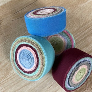 May include: Four rolls of fabric scraps in various colors, including blue, green, pink, and burgundy. The fabric is rolled into a circle and has a raw edge.