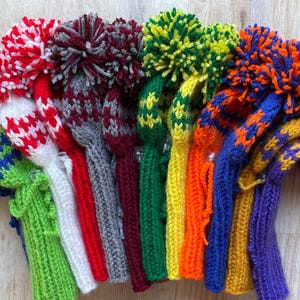 May include: A set of ten knitted golf club head covers with pom-poms. The covers are in various colors, including green, red, white, blue, yellow, and orange.